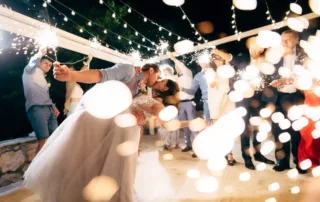 groom and bride kissing among guests with sparklers at the wedding party